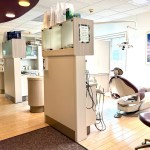 An open-concept dental clinic showing a modern treatment bay with a purple patient chair and organized medical storage units.
