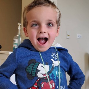 A young boy with his mouth open, showing off his teeth in a happy manner